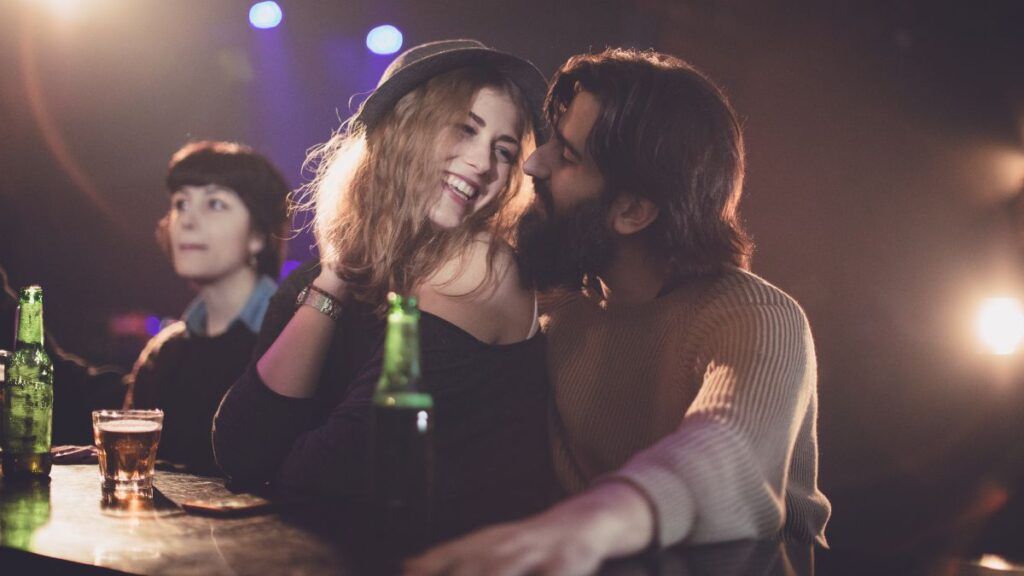 Mujer y hombre jóvenes hablan en un bar. Encuentra mujeres buscando pareja con estos consejos.